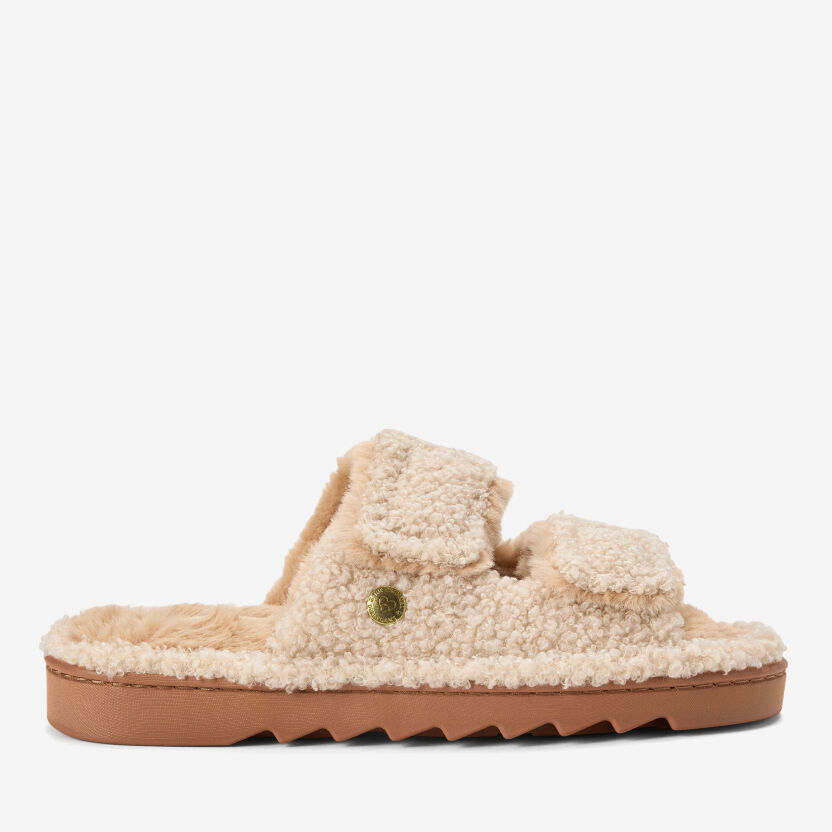 Cream sherpa double-strap slide slippers with adjustable buckles and a chunky textured sole, shown in side profile.