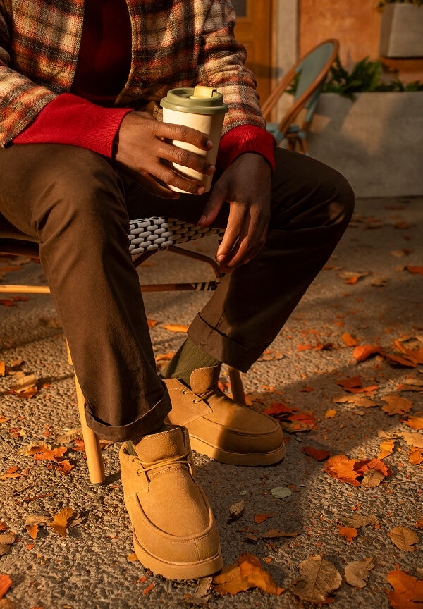 Person seated outdoors in autumn wearing tan boots with brown pants and socks.