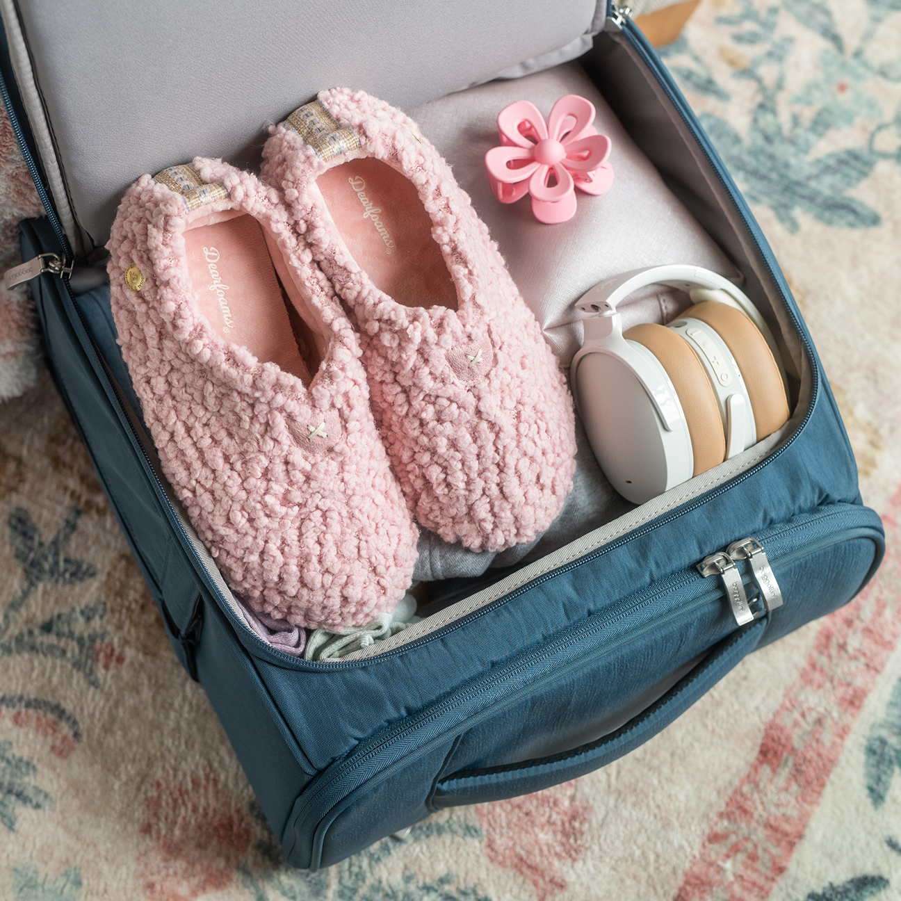 Pink textured knit slipper socks packed inside a suitcase beside headphones and travel essentials, ready for comfortable travel.