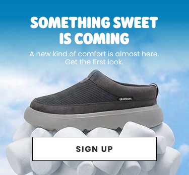 Something sweet is coming. A new kind of comfort is almost here. Get the first look. Sign up to stay in the know. Gray Dearfoams Marshmellow slip-on displayed on a pile of white marshmallows against a blue sky.